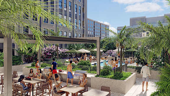 A group of people are sitting and standing on a patio with a pool.