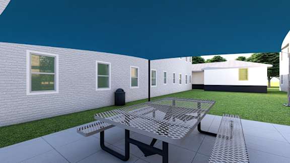 a patio with a table and chairs and a green lawn