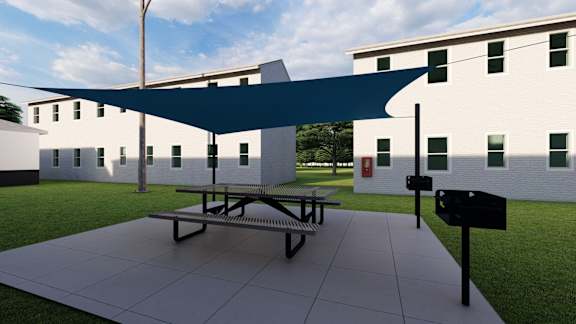 a picnic table with a blue canopy in front of a building