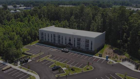 A large white building with a parking lot in front of it.