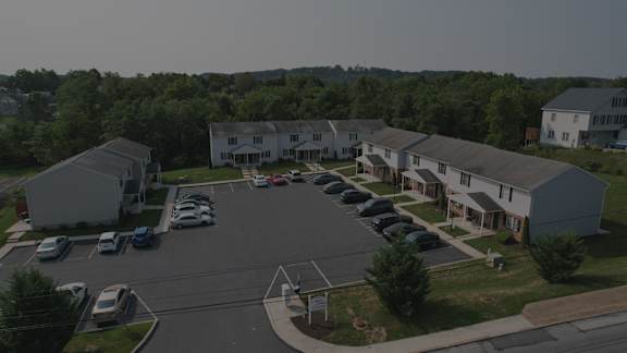 A parking lot in front of a residential area with cars parked.