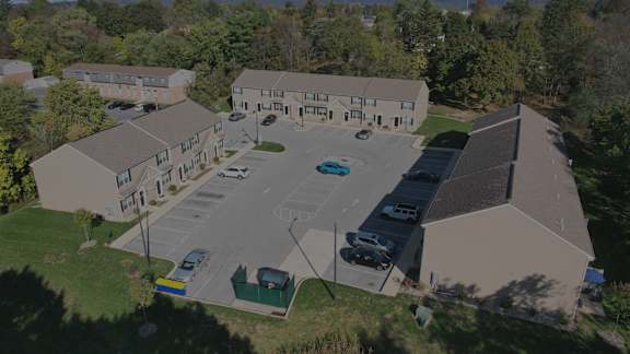A parking lot in front of a building surrounded by trees.