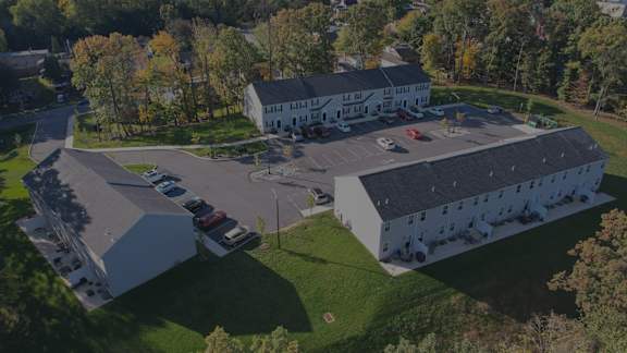 An aerial view of a white building with a parking lot in front.