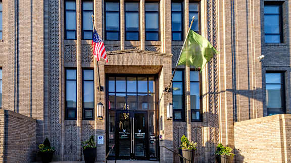 A building with a brown facade and a flag on the left side.