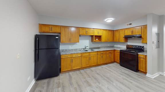 a kitchen with wooden cabinets and a black refrigerator
