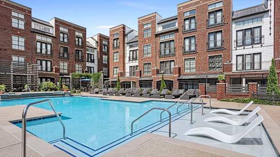 A swimming pool surrounded by lounge chairs and buildings.