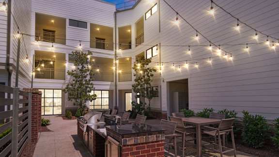 A patio with a table and chairs is illuminated by string lights.
