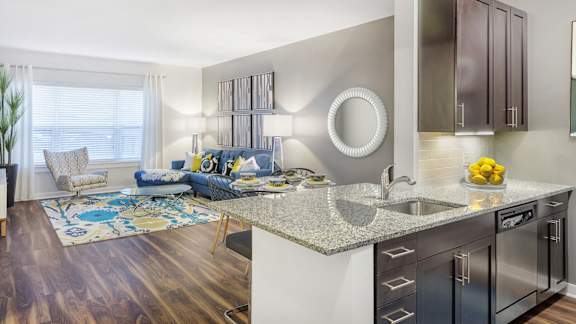 A modern kitchen with a blue sofa and wooden floors.