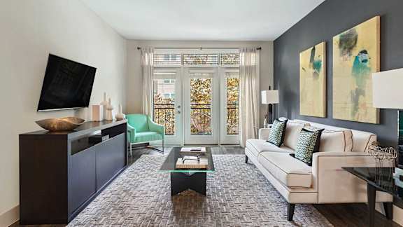 A living room with a white couch, a coffee table, and a television.
