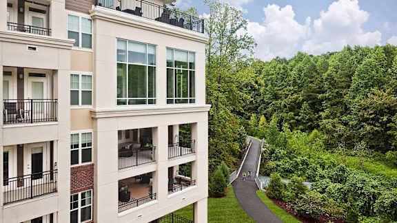 A building with a balcony overlooking a tree-filled landscape.