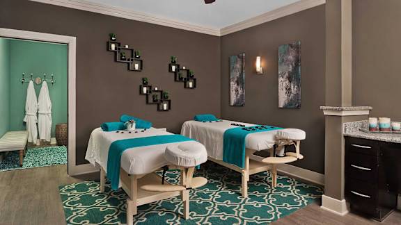 A room with two massage tables and a green patterned rug.