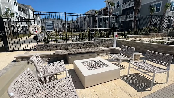 A patio with a fire pit and chairs.