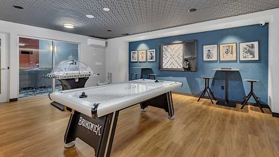 A room with a pool table and a bar stool.