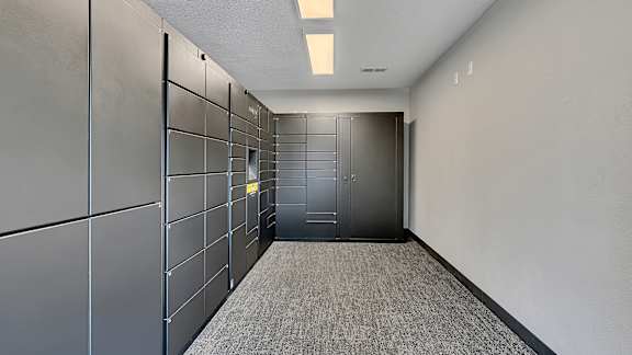 A long hallway with a carpeted floor and a series of metal lockers on the wall.