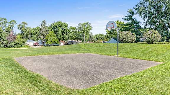 a basketball court in the middle of a grass field