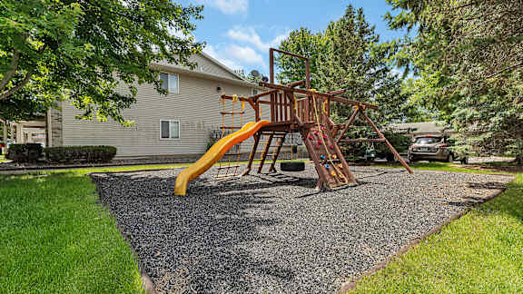 a swing set with a yellow slide in a backyard