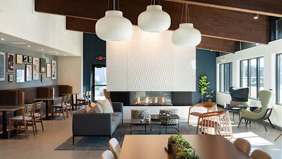 a living room with a fireplace and a table and chairs at The Bosk Apartment Homes, Woodbury, 55125