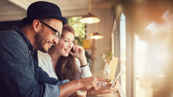 a man and a woman looking at a tablet in a coffee shop