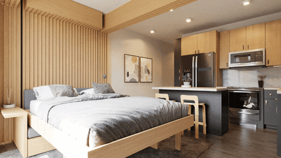 A bedroom with a bed, nightstand, and a kitchen area with a refrigerator, microwave, and oven.
