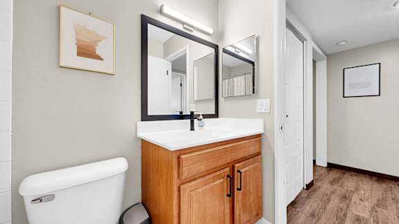 A bathroom with a white toilet and a wooden cabinet.