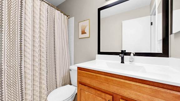 A bathroom with a toilet, sink, and a mirror.
