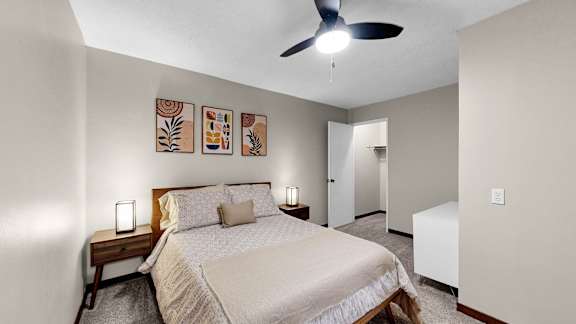 A bedroom with a bed, nightstand, and a ceiling fan.