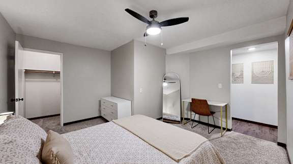 A bedroom with a bed, chair, and desk.