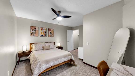 A bedroom with a bed, a chair, and a ceiling fan.