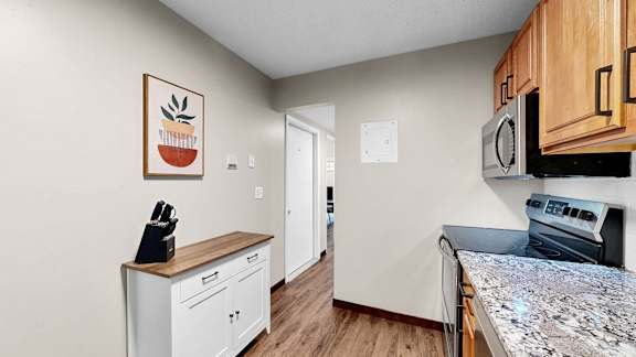 A kitchen with a granite countertop and wooden cabinets.