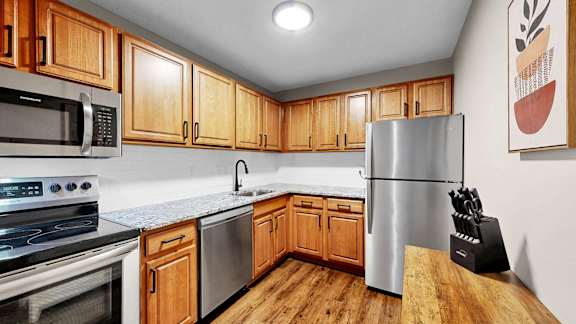 A kitchen with wooden cabinets and a stainless steel refrigerator.