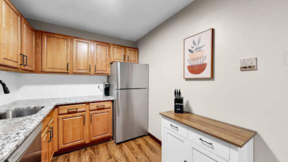A kitchen with wooden cabinets and a stainless steel refrigerator.