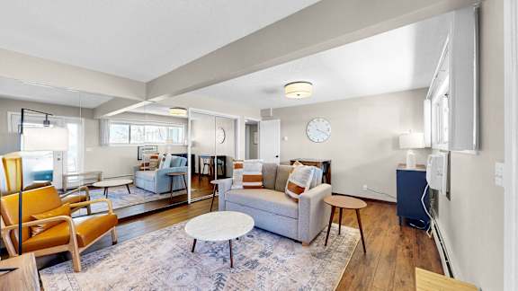 A living room with a couch, chairs, and a rug.