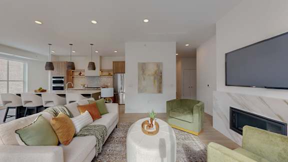 A modern living room with a white couch, green armchair, and a coffee table with a small potted plant on it.