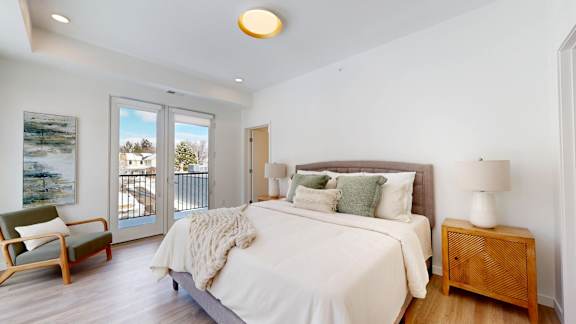 A bedroom with a large bed, a chair, and a painting on the wall.