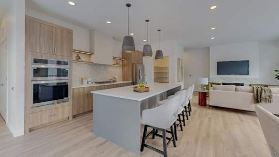 A modern kitchen with a large island and a TV mounted on the wall.