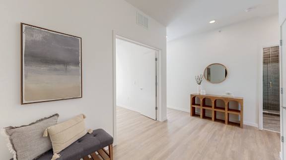 A room with a grey couch and a painting on the wall.