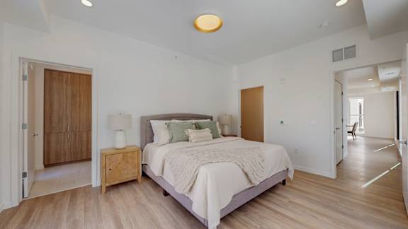 A bedroom with a bed, nightstand, and a wooden door.