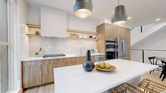 A modern kitchen with a white island and wooden cabinets.