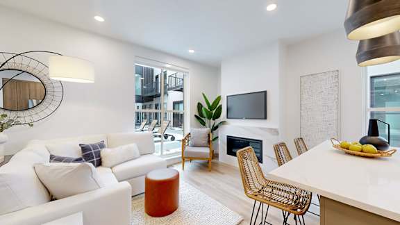 A modern living room with a white sofa, a wooden coffee table, and a TV mounted on the wall.
