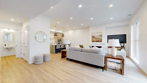 A modern living room with a grey sofa and wooden floors.