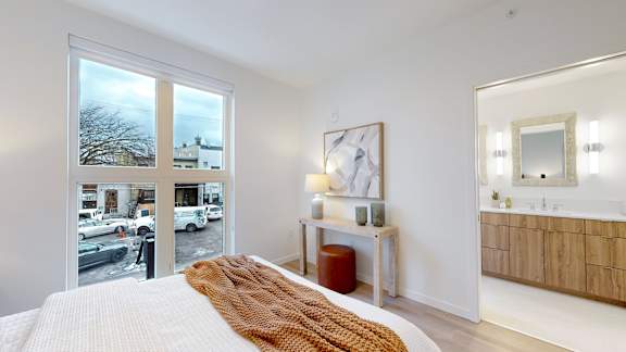A bedroom with a large bed and a view of the street outside.