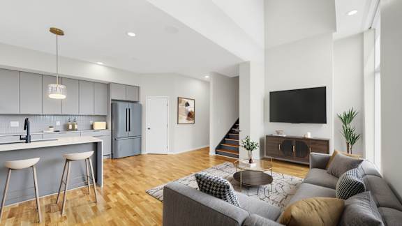 A modern living room with a grey sofa and a wooden floor.