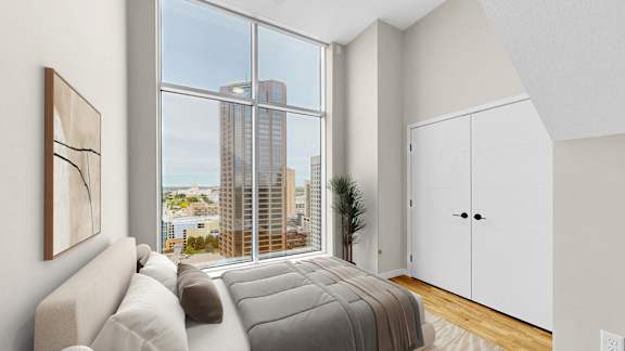 A modern bedroom with a large window overlooking the city.