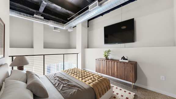 A bedroom with a bed, a couch, a TV, and a window with blinds.