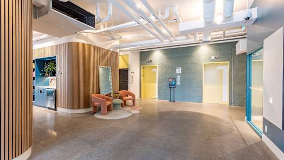 a large lobby with a yellow door and orange chairs in it