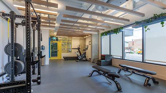 a fitness room with weights and cardio equipment and windows