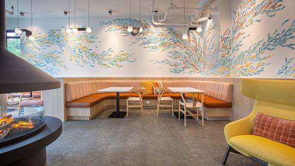 a dining room with tables and chairs and a mural on the wall