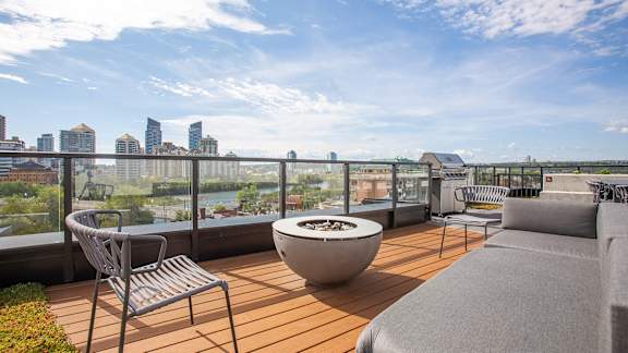 a balcony with a couch and chairs and a fire pit