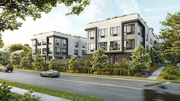 A modern apartment building with a car driving by on the street.