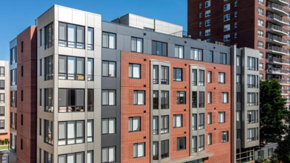 A modern multi-story building with red brick and grey panels.